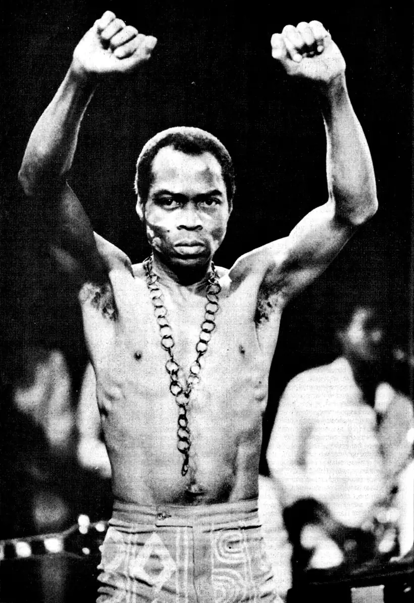 Fela Anikulapo Kuti on stage, bare-chested, both fists raised, around 1986.