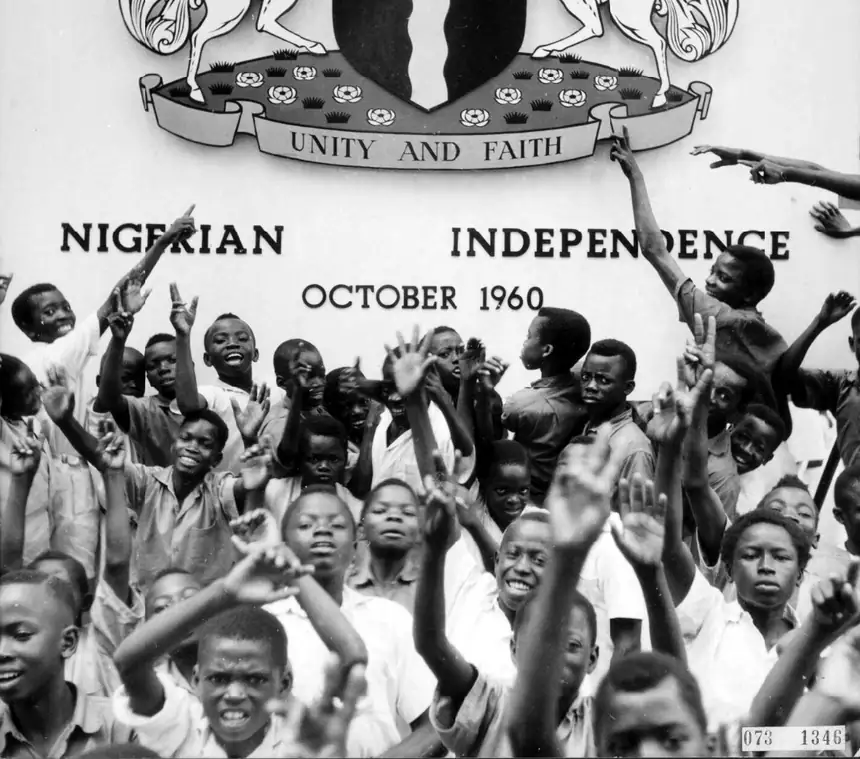 Black and white photograph of young children waving small flags at Nigeria’s independence celebration, 1960.
